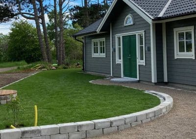 en grå villa med gräsmatta och grå kantsten
